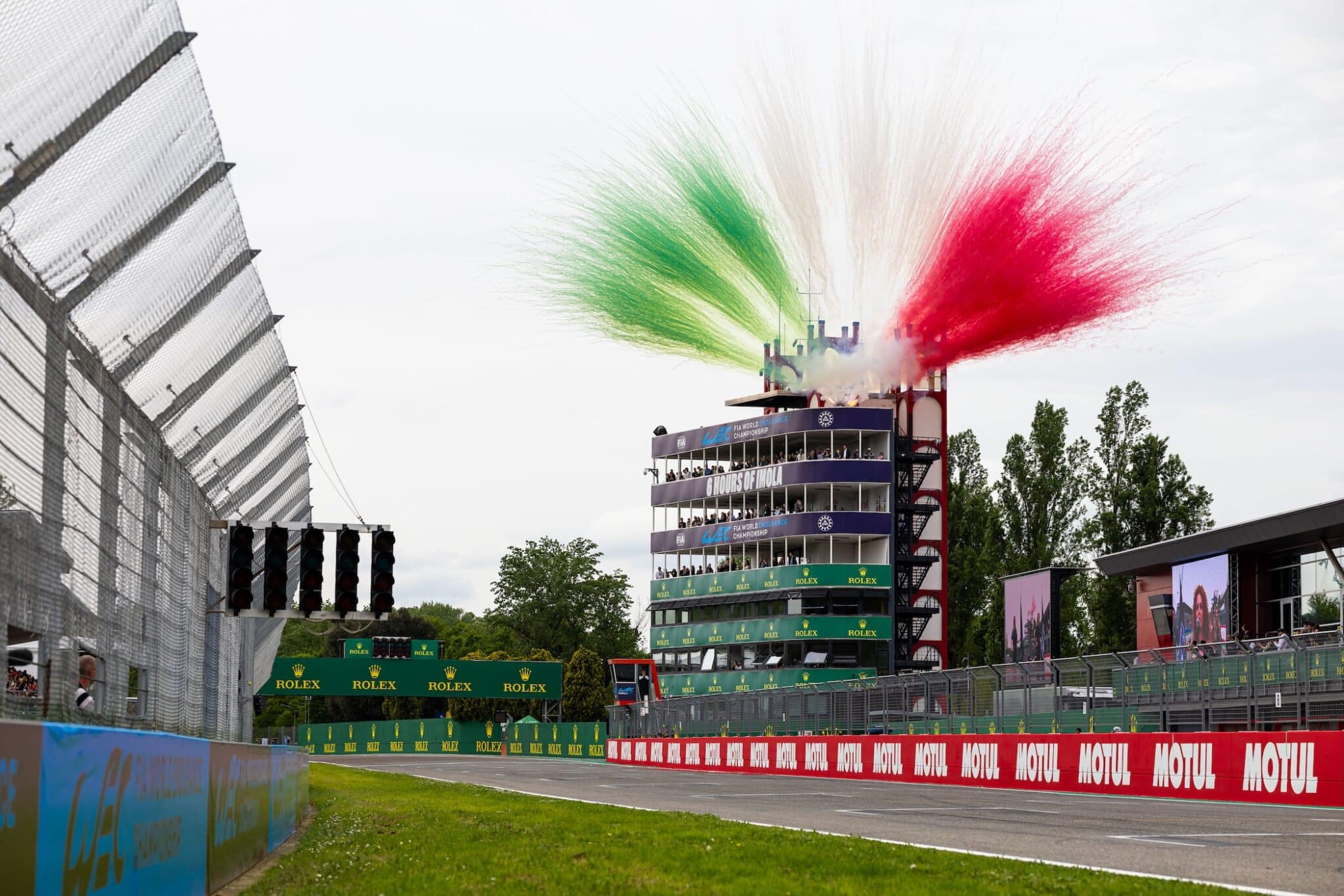 La torre dell'Autodromo di Imola avvolta da fumi tricolore durante il FIA WEC. Domani accoglierà la fiamma olimpica di Milano Cortina 2026.
