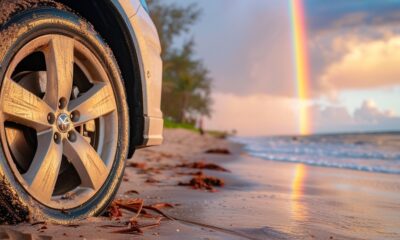 Auto su una spiaggia con l'arcobaleno